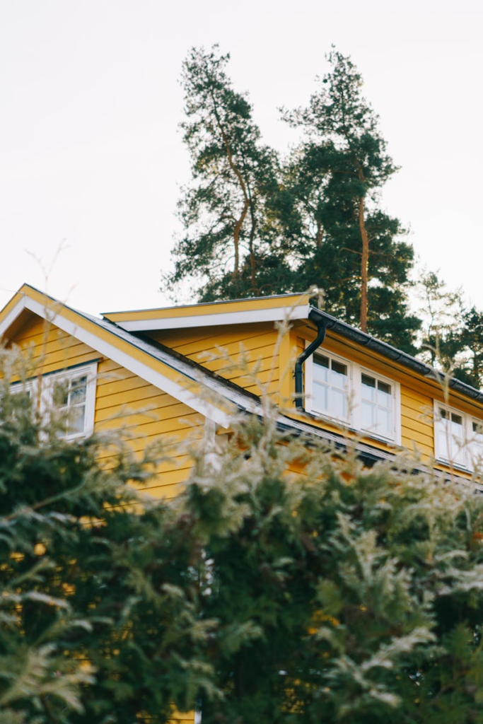 A picturesque yellow house surrounded by lush green trees, ideal for country living.